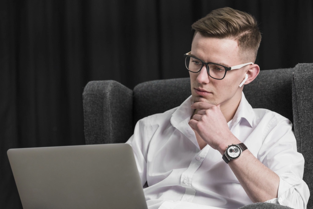 portrait-handsome-young-man-sitting-armchair-looking-laptop_1.webp